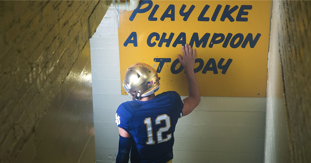 This image captures a Notre Dame football player touching the iconic "Play Like a Champion Today" sign before a game. This action is a long-standing tradition for the University of Notre Dame football team, intended to inspire players before they run onto the field. The sign is located in the tunnel leading from the locker room to the field at Notre Dame Stadium. Every player on the team typically touches the sign as they head out to play. The sign is a significant symbol of the team's spirit and tradition. Write Like Scholars Today - LinkedIn Apr 18, 2023 — Each Notre Dame football team player slaps the "Play Like a Champion Today" sign before each game. https://www.linkedin.com/pulse/write-like-scholars-today-matt-ferdock-ph-d-