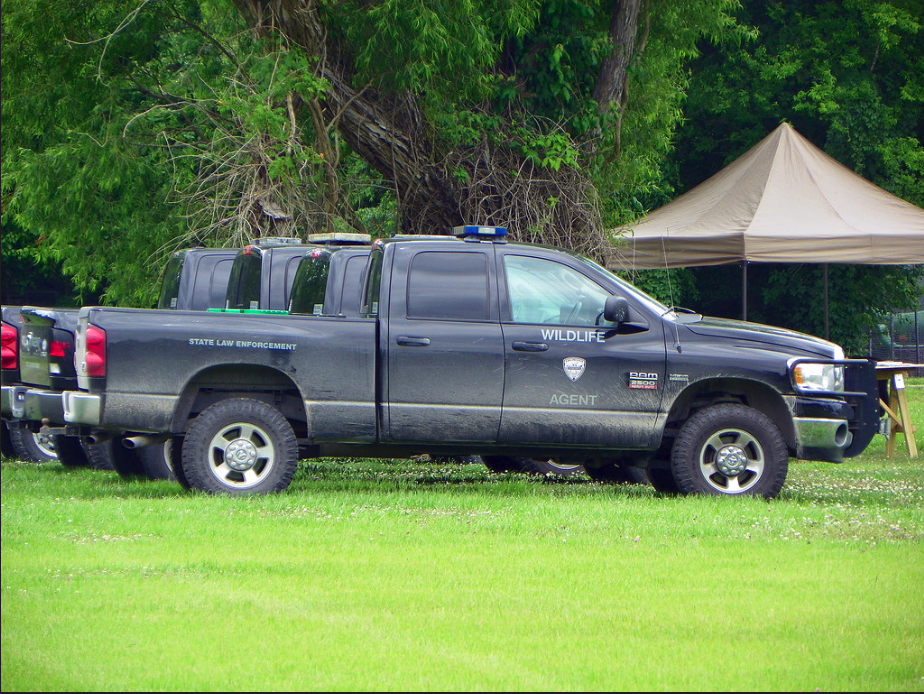 Image of Louisiana game warden trucks parked at a community event. The 287(g) program allows local officers to detain and transfer people to ICE and wildlife agencies are participating directly.